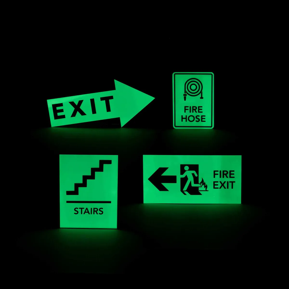 Plaques signalétiques photoluminescentes vertes visibles dans le noir : sortie (EXIT), tuyau incendie, escalier et issue de secours